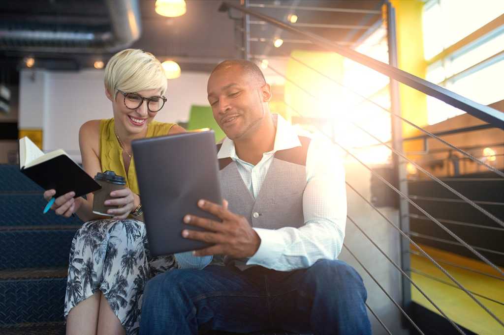 business people sitting on steps and having a conversation while using a tablet