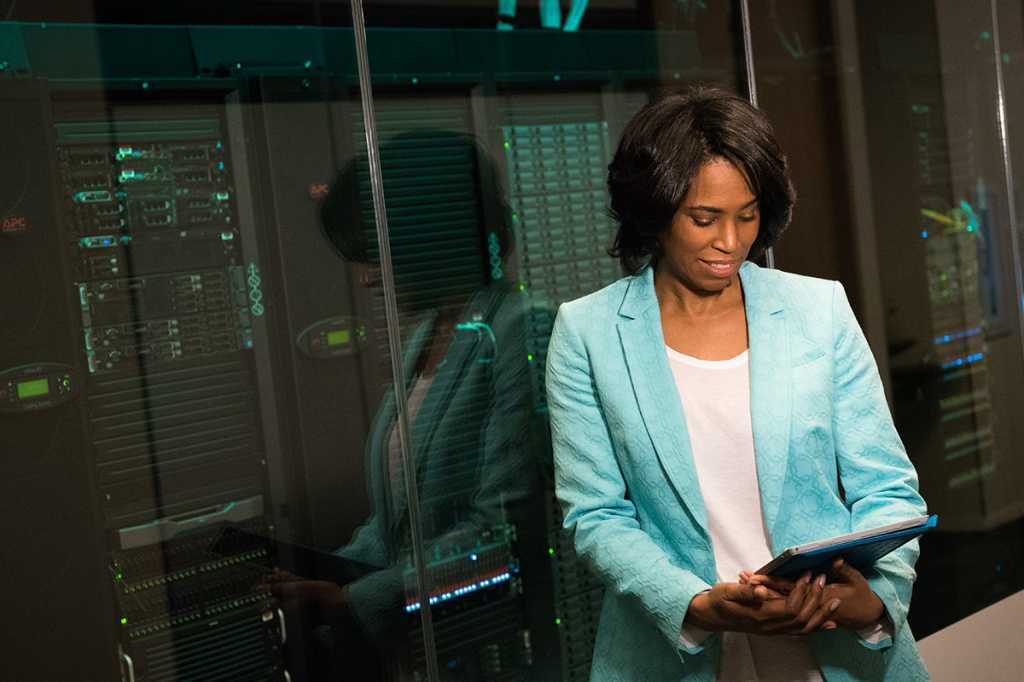 developer / administrator / a woman uses a Surface tablet near data center, servers