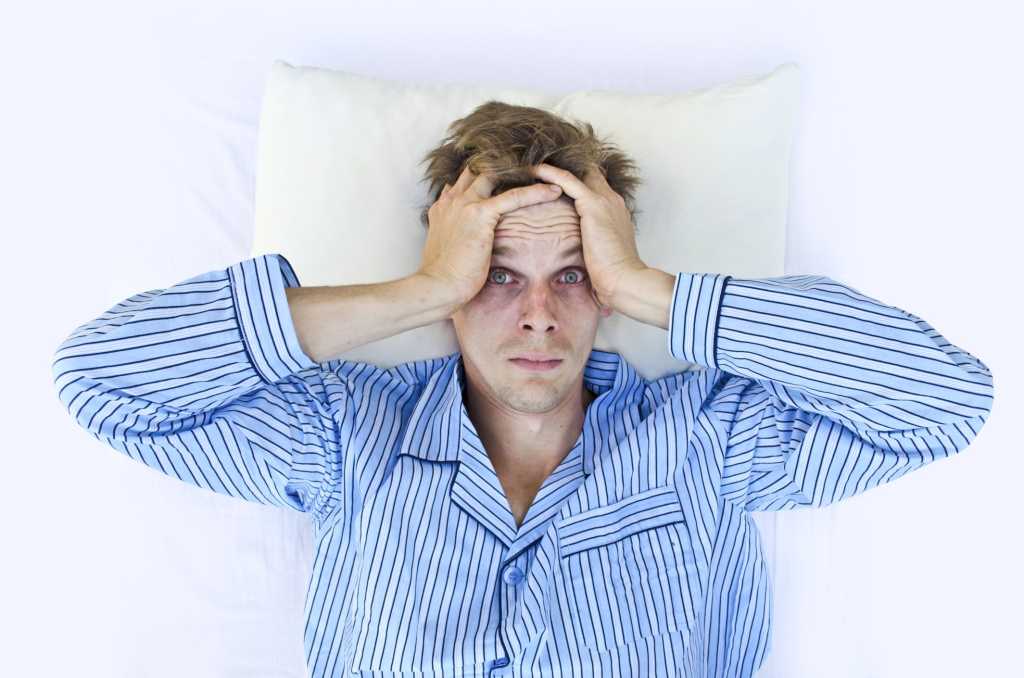 Man in pajamas in bed unable to sleep insomniac