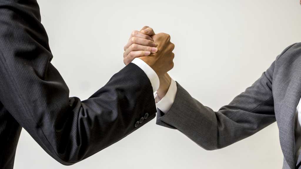 Two business people in suits locking hands.